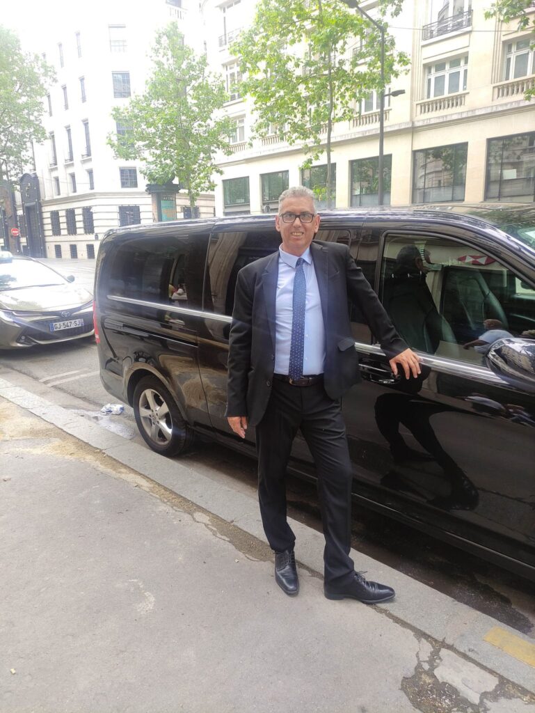 Chauffeur privé Booking Paris Transfer à côté d’un van Mercedes