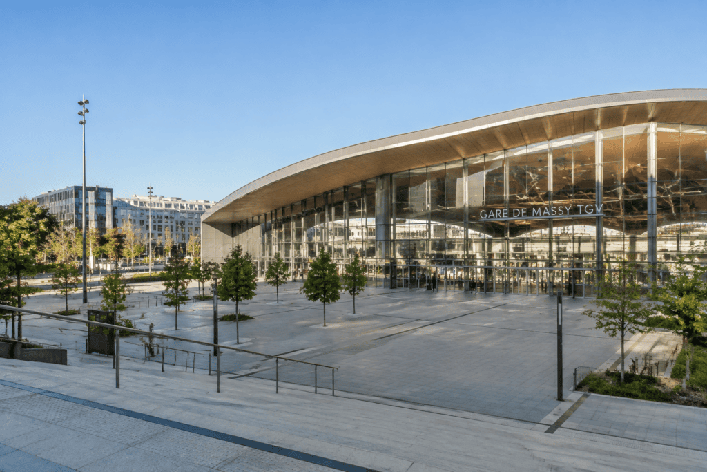Façade vitrée de la gare de Massy TGV donnant sur un vaste parvis arboré.