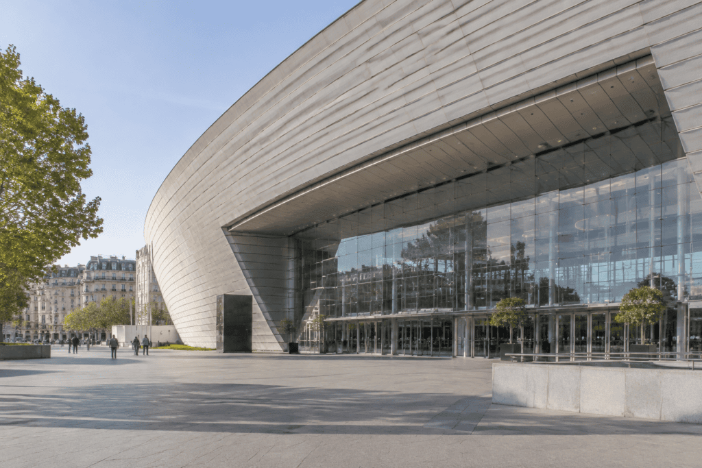Façade courbe et entrée vitrée du Palais des Congrès, ouvrant sur un vaste parvis pavé.