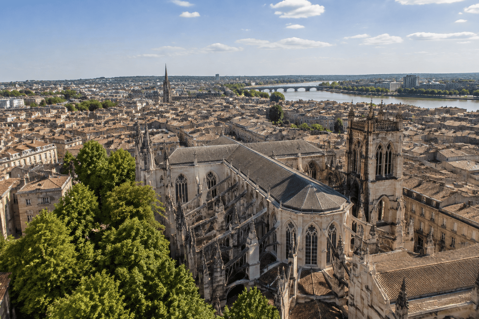 A Gothic cathedral towers over a city's rooftops, with a river and a bridge in the background.