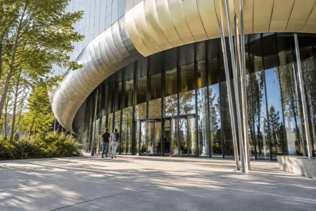 Façade vitrée de la Cité du Vin sous une large avancée métallique courbe, avec deux personnes devant l’entrée.