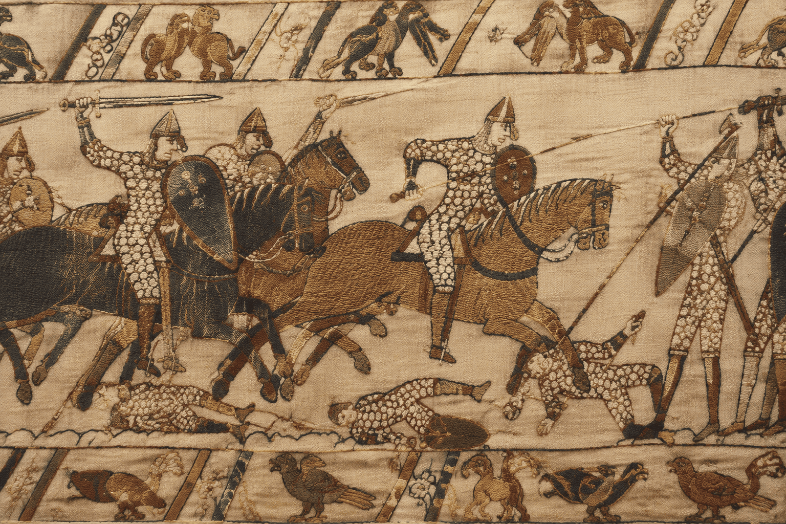 Détail brodé montrant des cavaliers casqués, des chevaux et des combattants, encadrés par des bordures figurées.