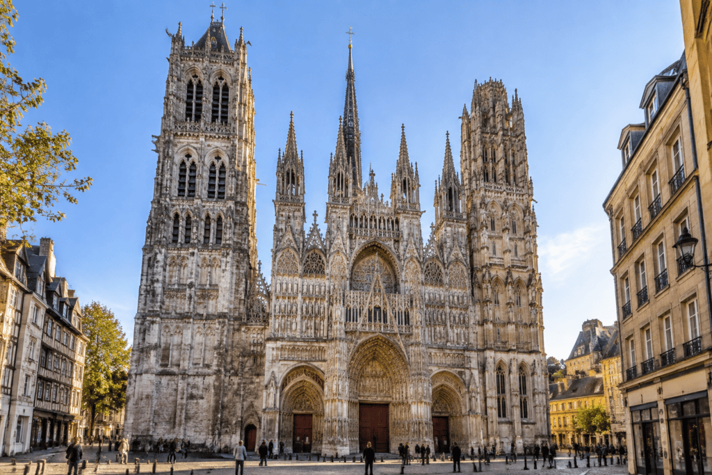 La façade gothique de la cathédrale de Rouen, avec ses portails sculptés et ses tours, bordée par les rues du centre ancien.