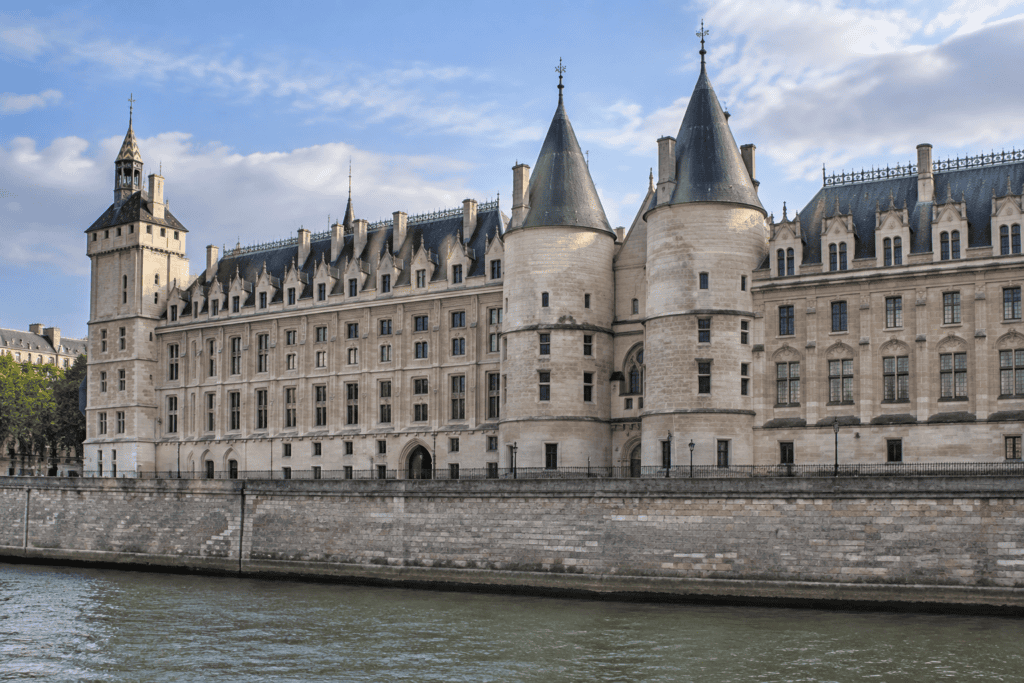 Longue façade de pierre de la Conciergerie, avec ses tours et ses toits, au-dessus de la Seine.