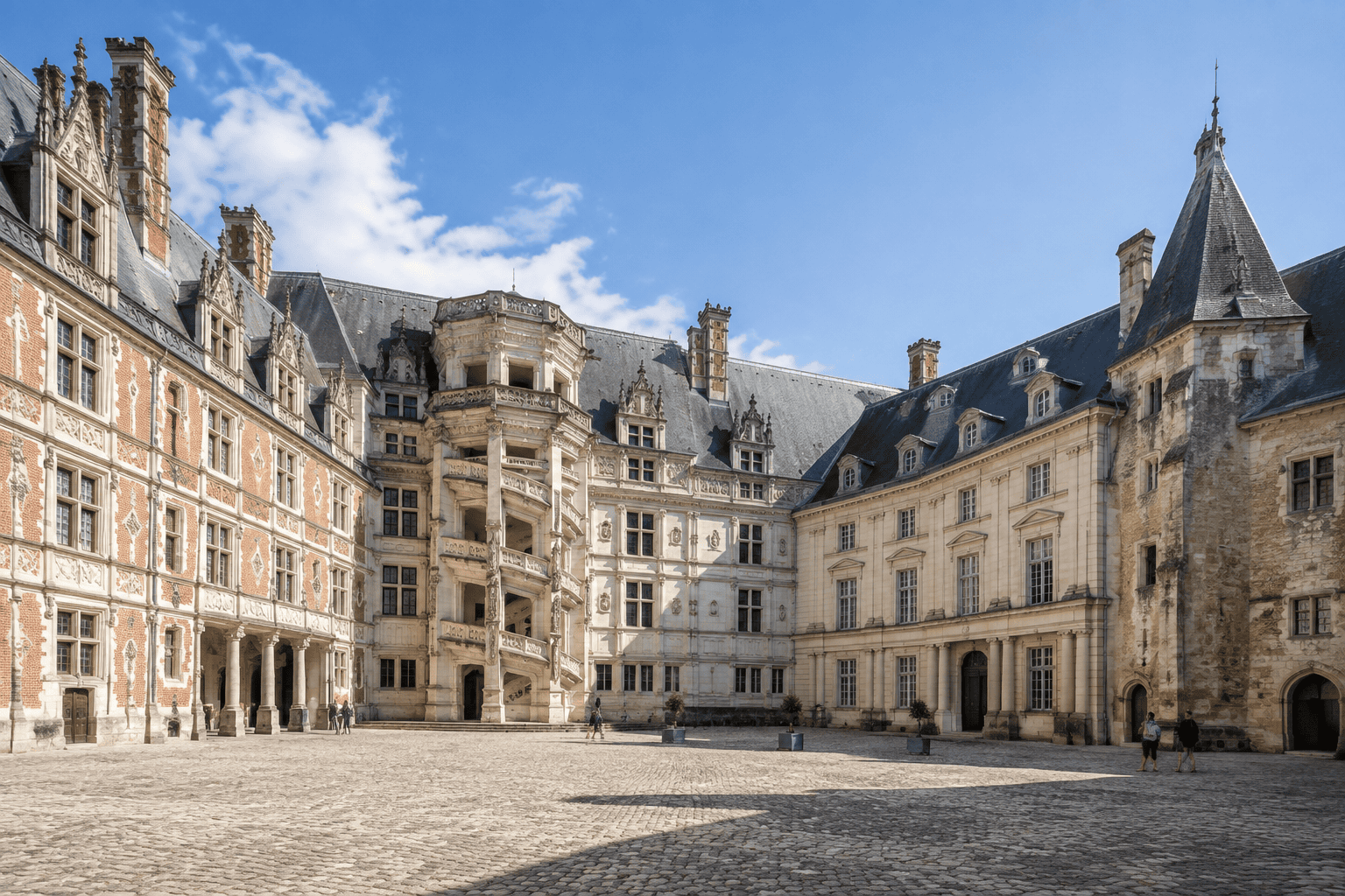 La cour pavée du Château royal de Blois, entourée de façades aux styles architecturaux contrastés.