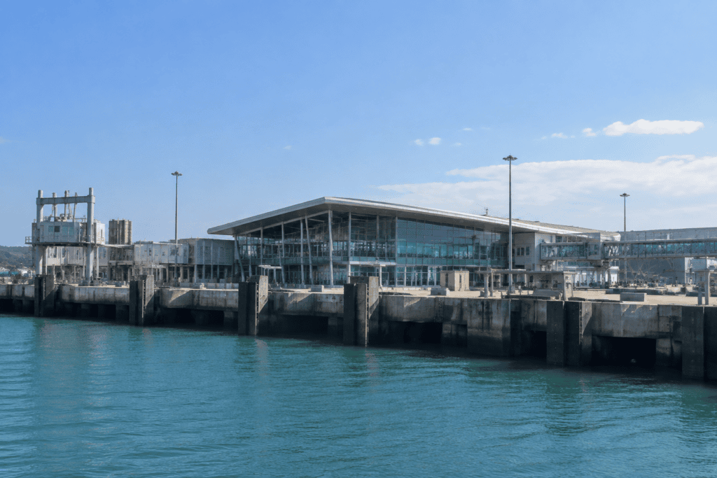 Bâtiment moderne vitré au bord d’un bassin portuaire, avec des quais au premier plan.