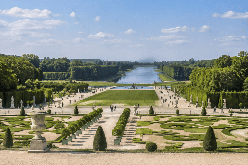 Vue des parterres géométriques et des allées des jardins de Versailles, avec le Grand Canal dans l’axe au loin.