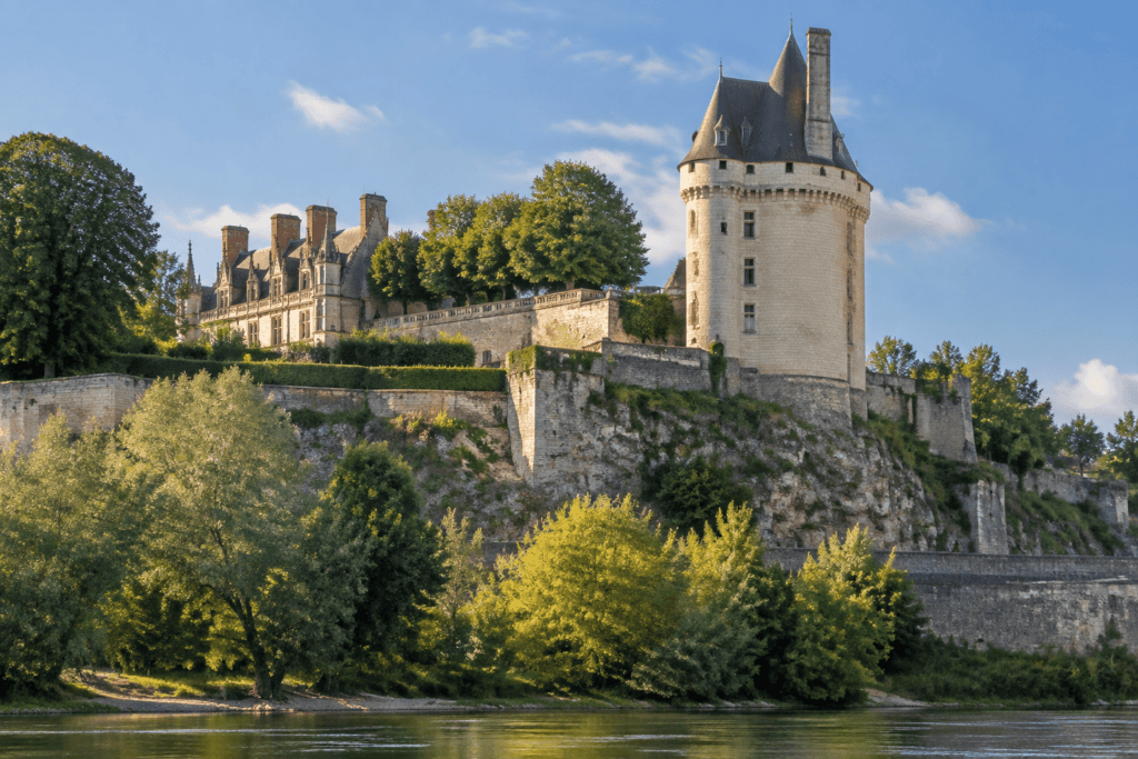 Une haute tour ronde en pierre domine les remparts du château d’Amboise, au-dessus des arbres et de la Loire.