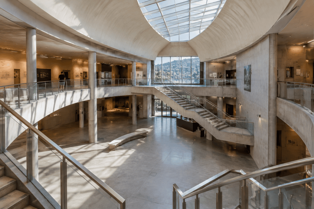 Atrium intérieur à deux niveaux, avec des galeries, un escalier central et une verrière au plafond.