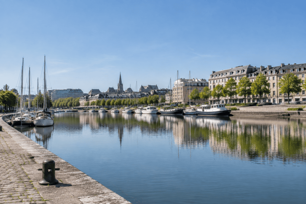 Bateaux amarrés sur un bassin bordé de quais et de bâtiments urbains, avec un clocher en arrière-plan.