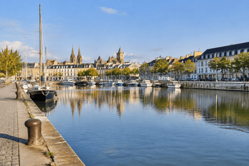 Bateaux amarrés sur le bassin Saint-Pierre, avec les quais et des bâtiments de Caen en arrière-plan.