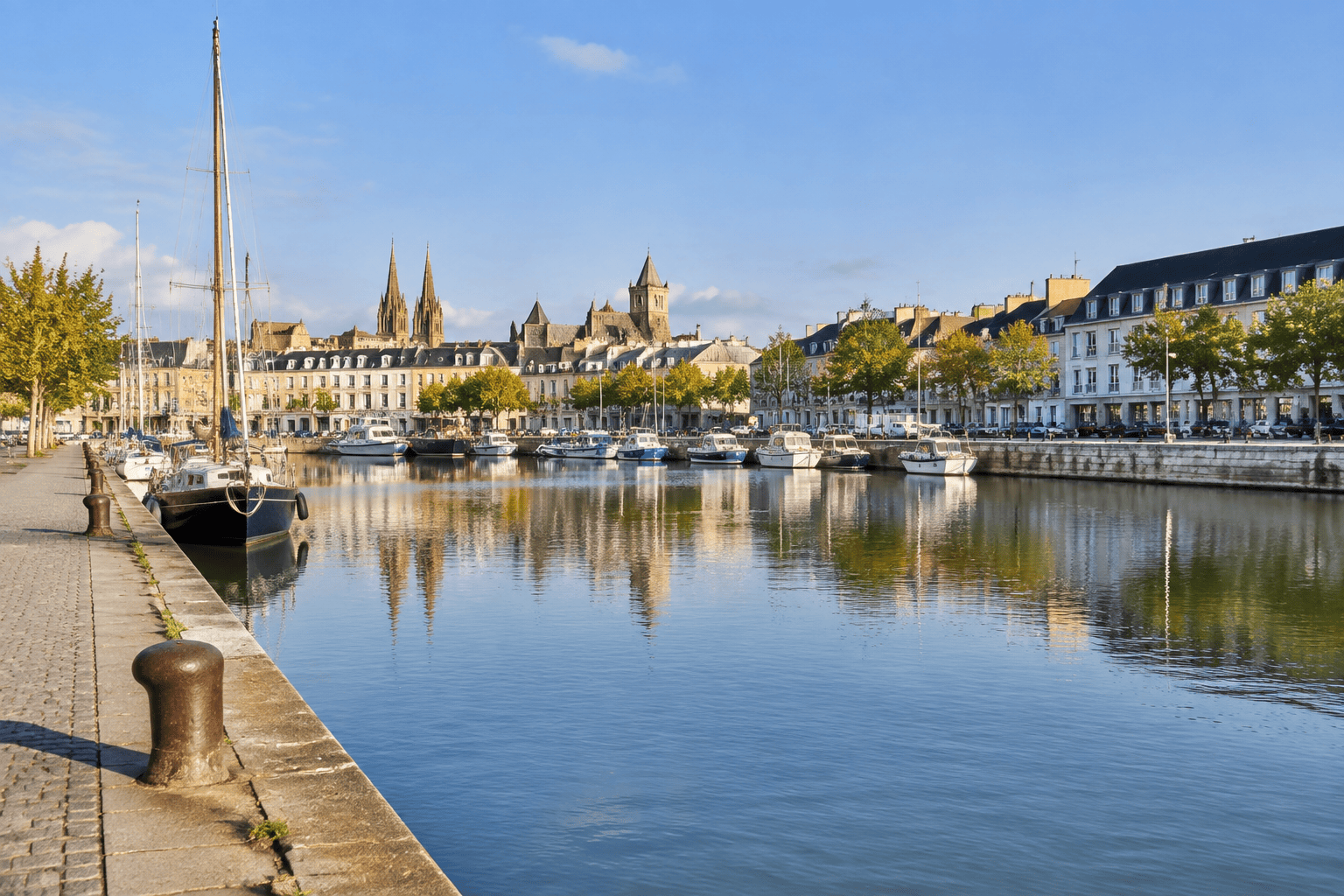 Bateaux amarrés sur le bassin Saint-Pierre, avec les quais et des bâtiments de Caen en arrière-plan.