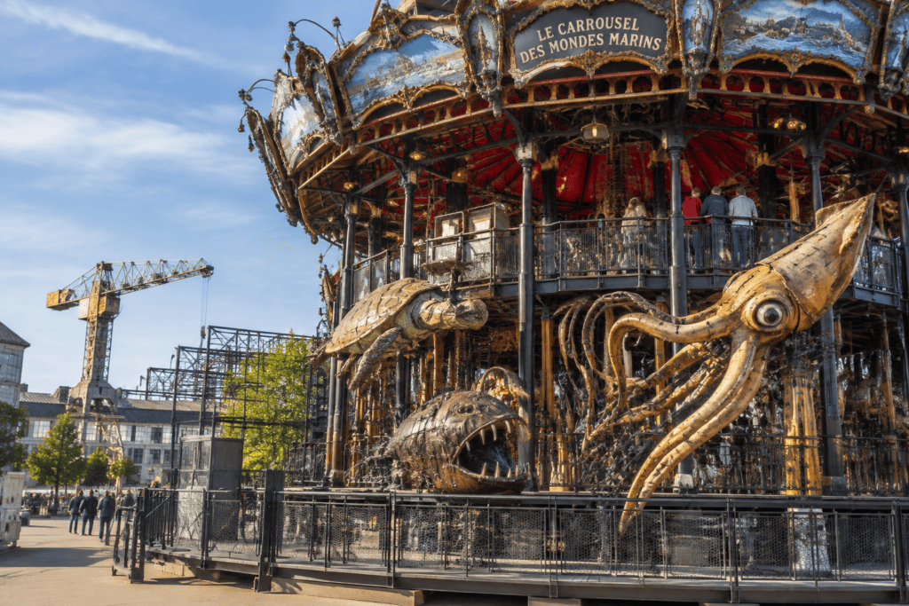 Le Carrousel des Mondes Marins avec une grande pieuvre mécanique et d’autres créatures marines devant sa structure circulaire.
