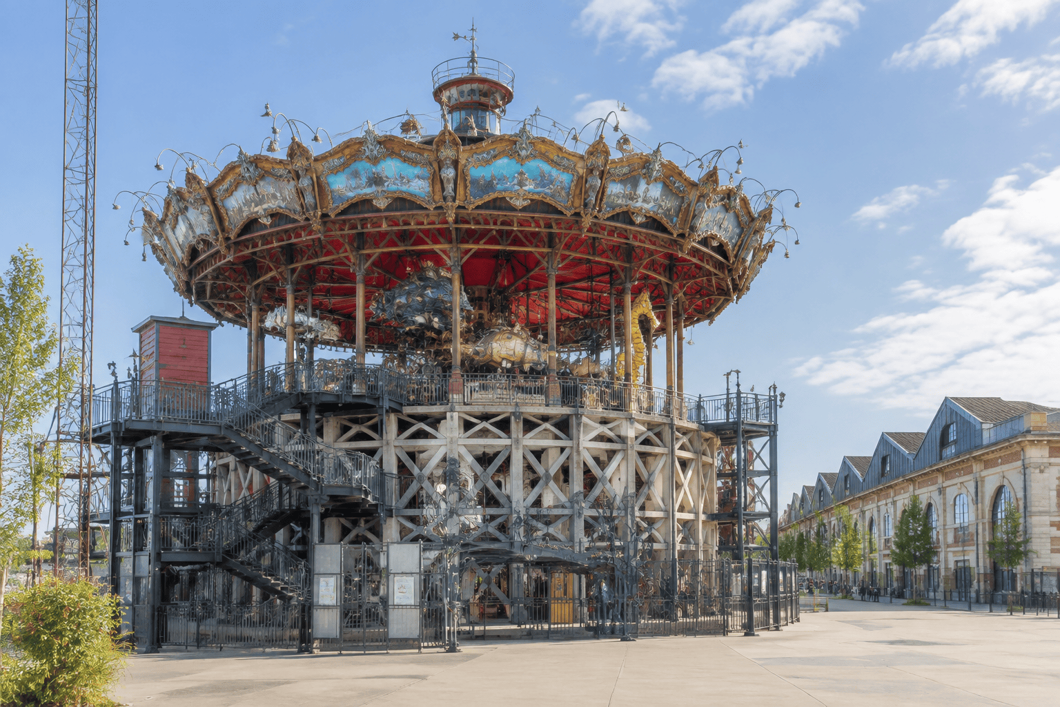 La structure circulaire surélevée du Carrousel des Mondes Marins, avec ses escaliers et ses ornements, se dresse devant un bâtiment industriel.