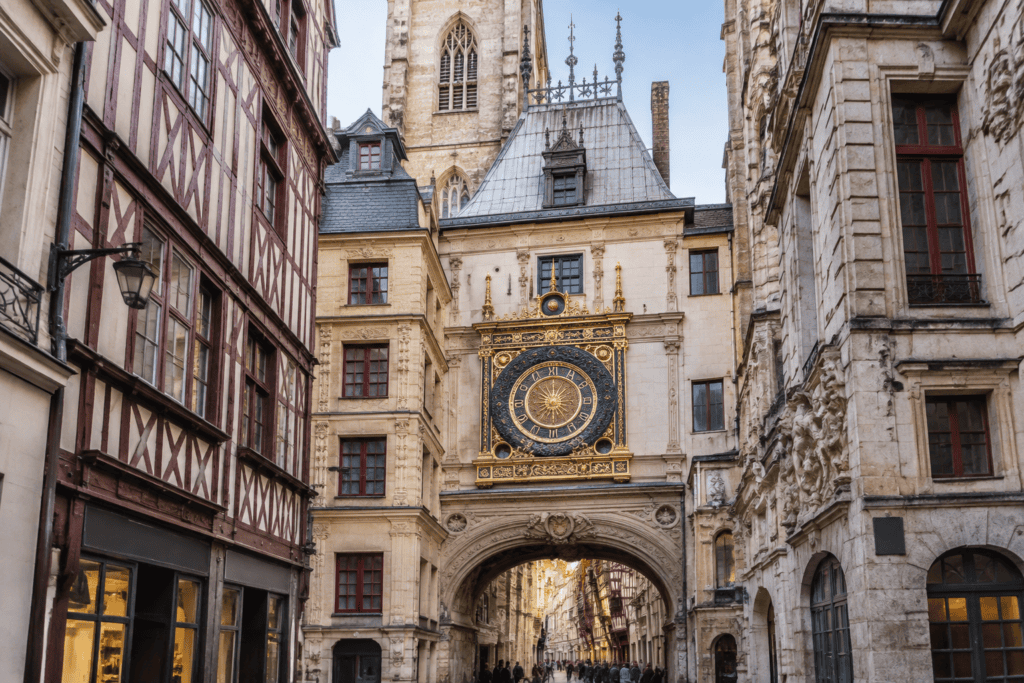 Le cadran doré du Gros-Horloge au-dessus d’une arche, entre des façades à pans de bois et des bâtiments en pierre.