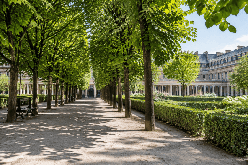 Allée ombragée bordée d’arbres et de haies, avec des façades à arcades en arrière-plan.