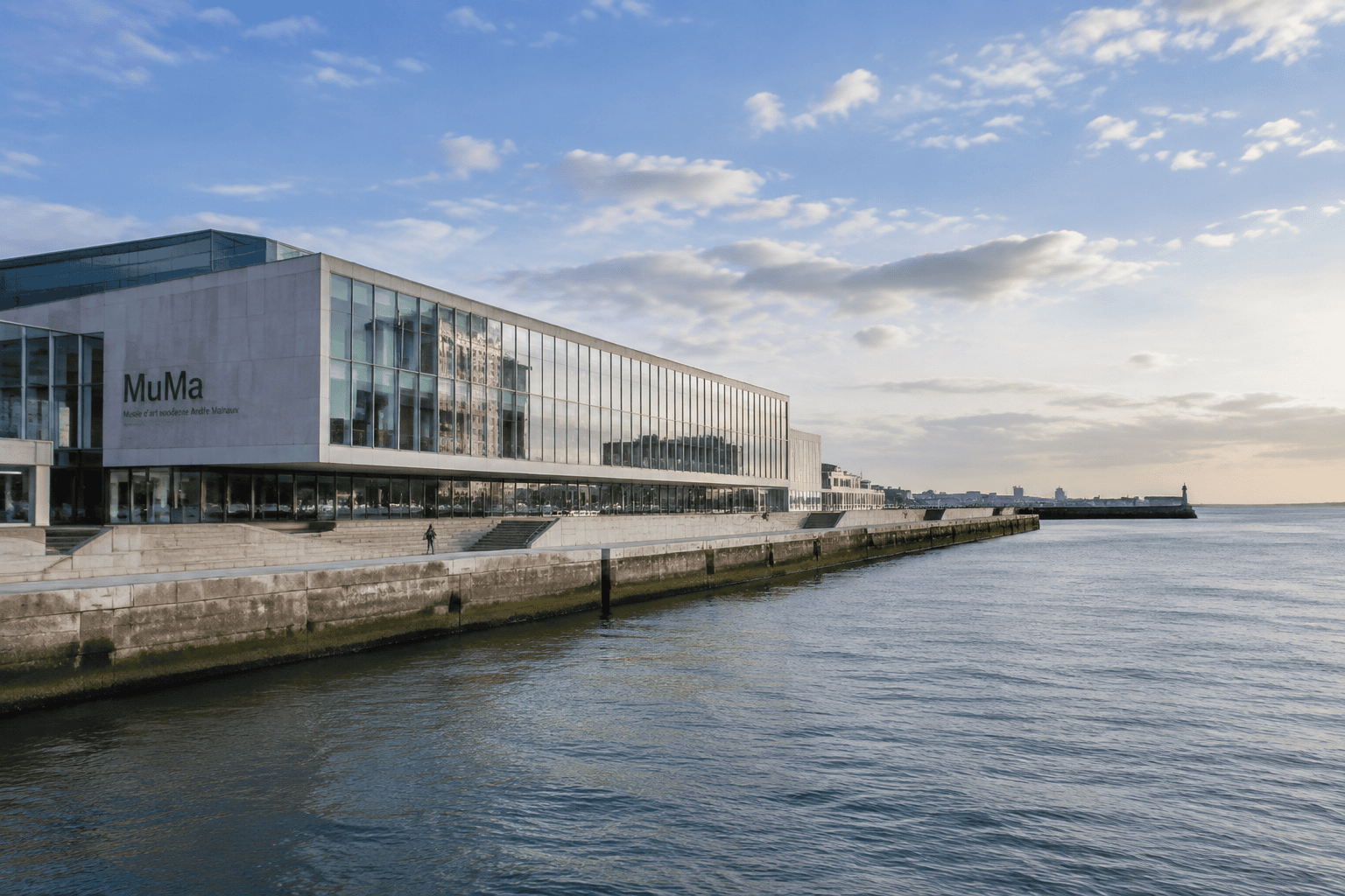 Façade vitrée du MuMa, avec son enseigne visible, longeant le quai au bord de l’eau.