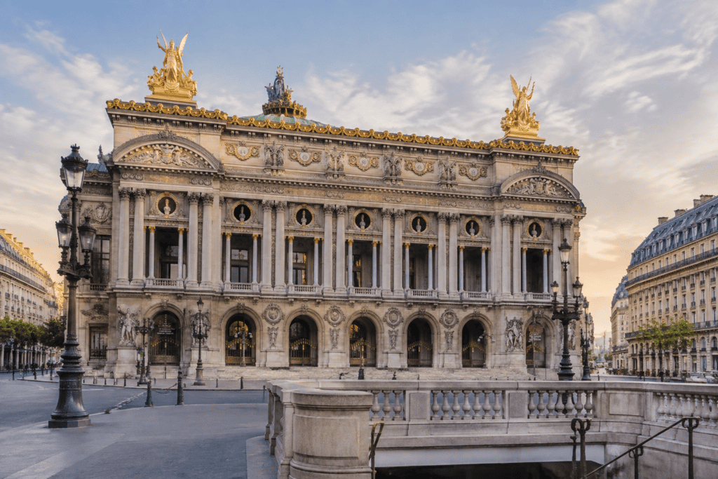 Façade ornée du Palais Garnier, avec ses colonnes, ses sculptures et ses statues dorées sur le toit.