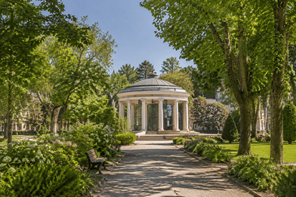 Allée arborée menant à une rotonde circulaire à colonnes dans un parc paysager.
