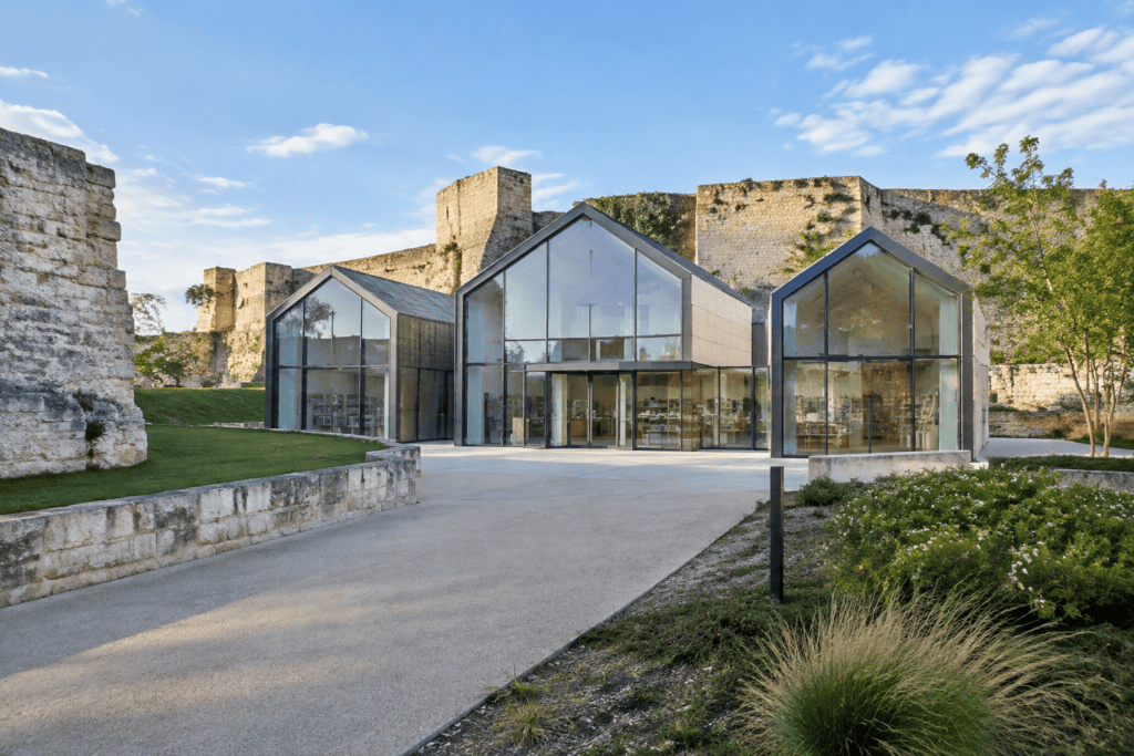 Pavillon contemporain composé de volumes vitrés devant les remparts en pierre du Château de Caen.