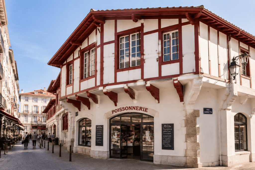 Façade blanche à colombages rouge sombre de la poissonnerie, avec son enseigne au-dessus de l’entrée et la plaque « Rue Gambetta ».
