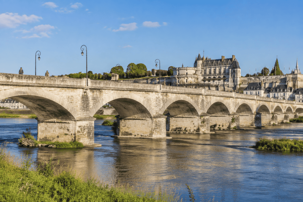 Le pont de pierre aux arches successives traverse la Loire, avec le château royal d’Amboise visible derrière lui.