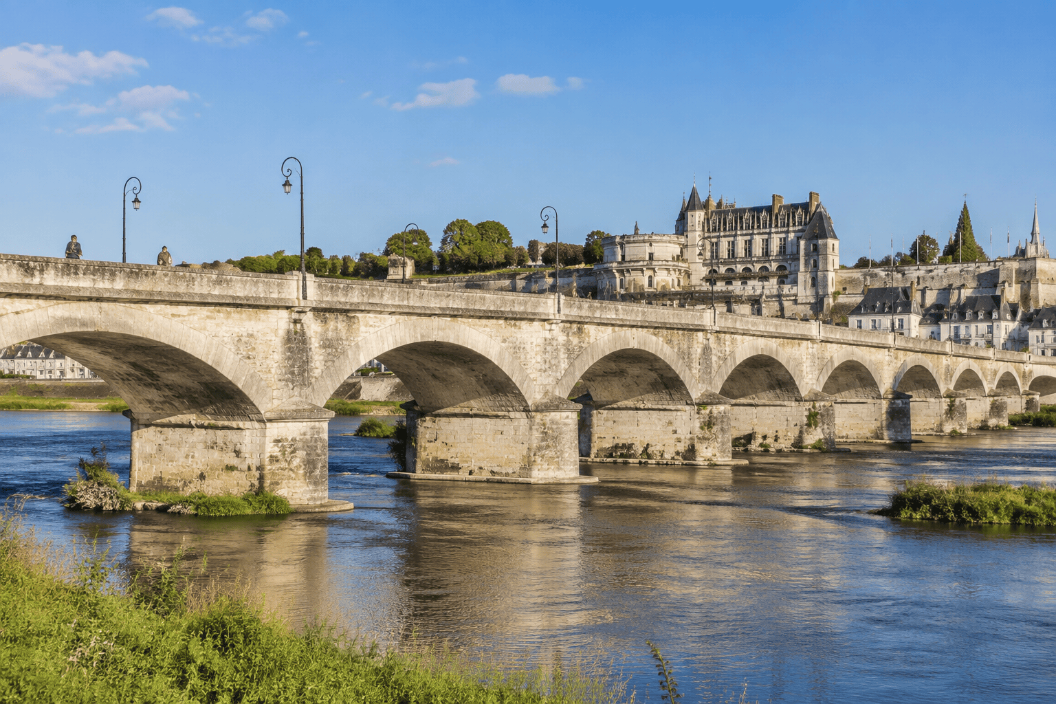 Le pont de pierre aux arches successives traverse la Loire, avec le château royal d’Amboise visible derrière lui.