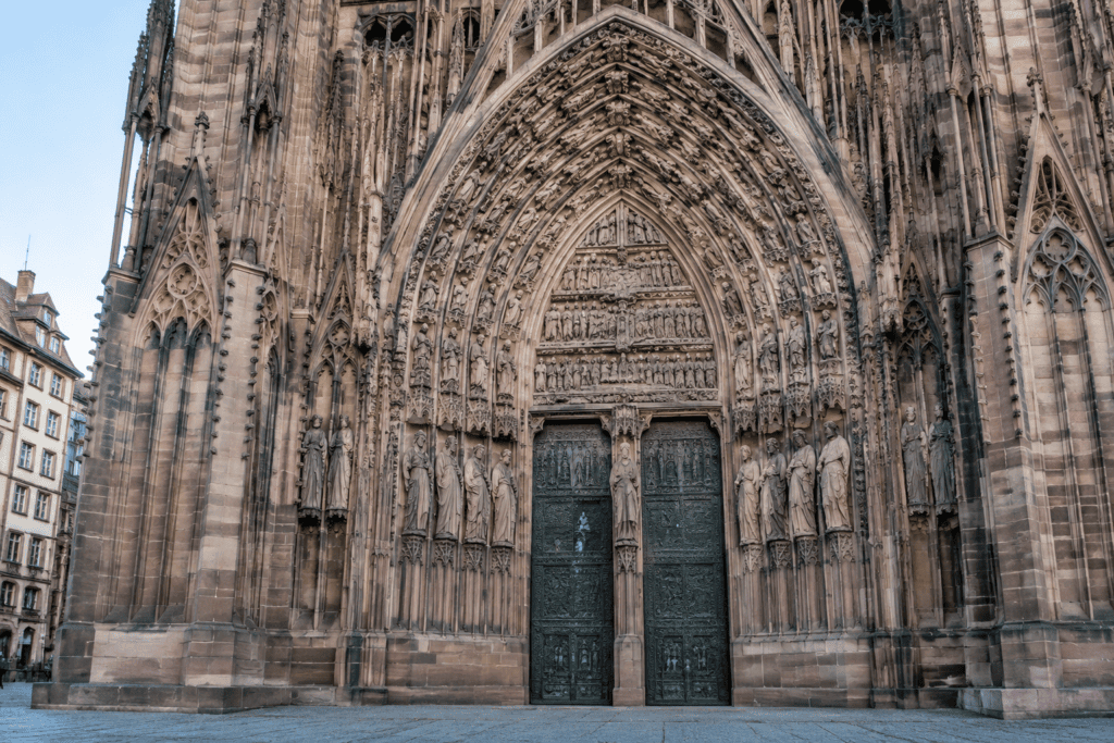 Portail gothique de la cathédrale de Strasbourg, avec ses portes, ses statues sculptées et ses voussures en pierre.