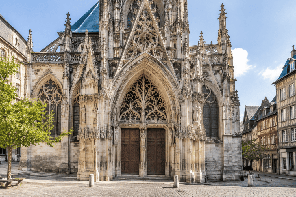 Façade en pierre de l’église Saint-Maclou, avec un grand portail gothique sculpté et ses portes en bois.
