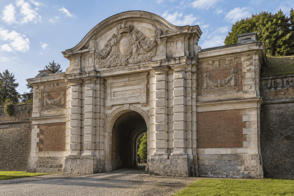 La Porte Royale, avec son fronton arrondi orné de sculptures, ses pilastres de pierre et ses ailes en brique et pierre.