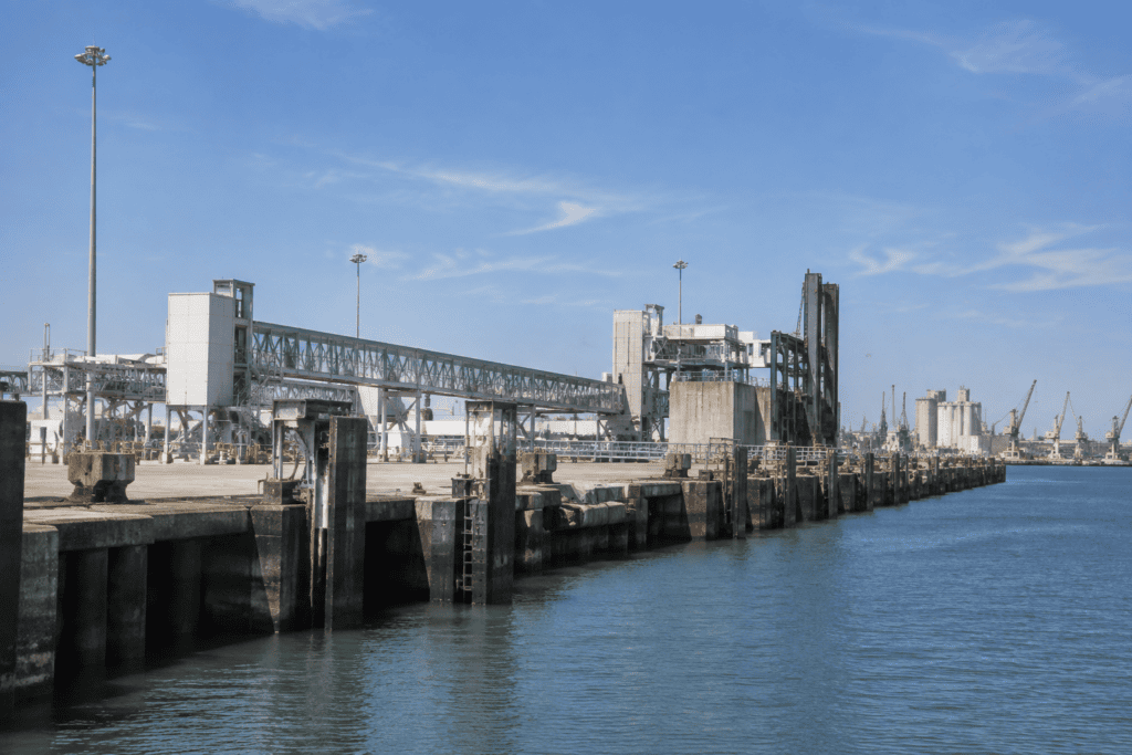 Quai industriel bordé d’eau, avec des structures de chargement et des équipements portuaires.