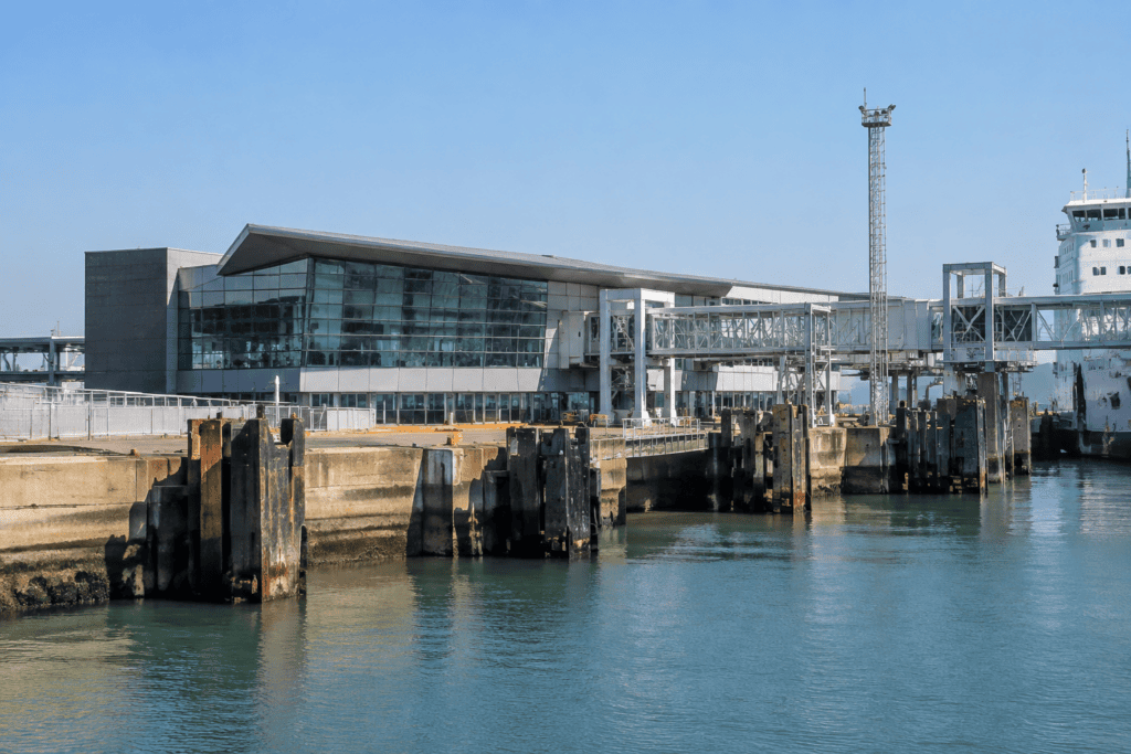 Bâtiment vitré au bord de l’eau, avec des passerelles portuaires au-dessus du bassin.