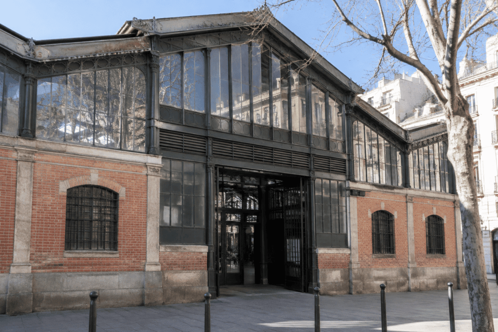 Façade vitrée et en brique d’une halle de marché, avec une entrée centrale donnant sur la rue.