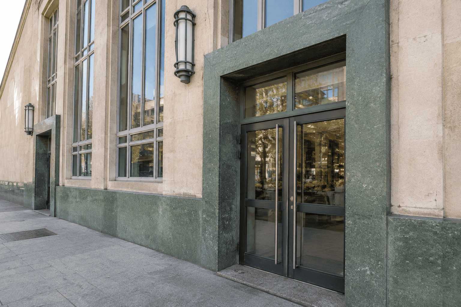 Porte vitrée encadrée de parement vert dans la façade des Halles du Boulingrin, à côté de hautes fenêtres.