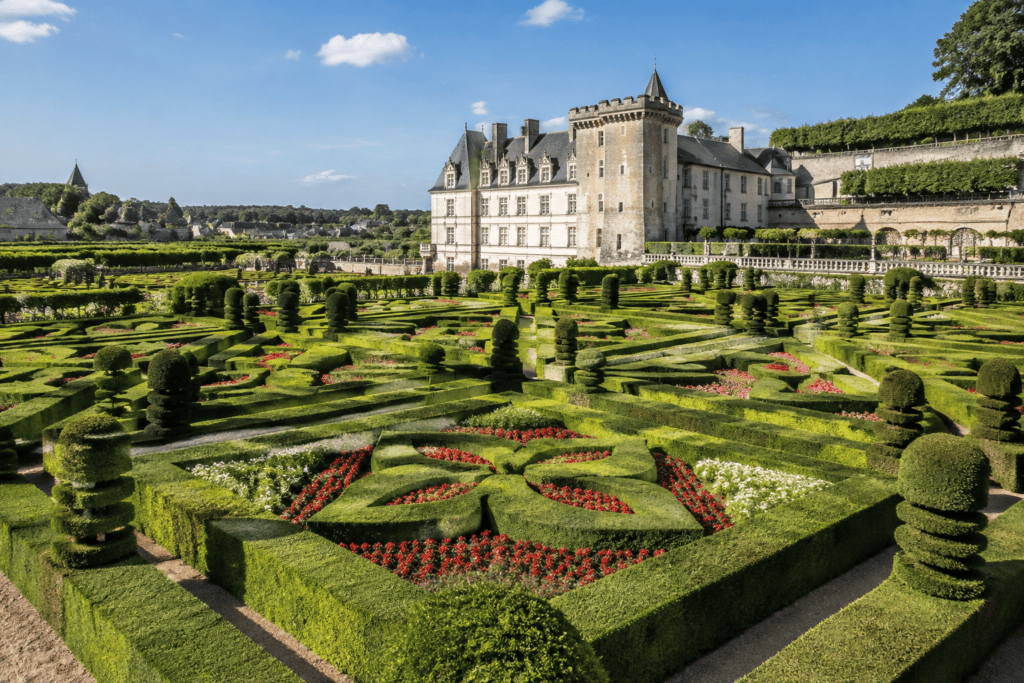 Parterres géométriques de haies taillées et fleurs rouges devant le château de Villandry.