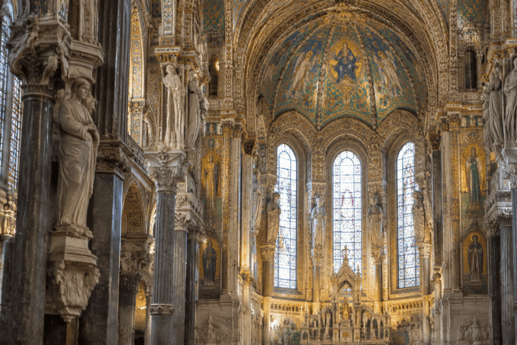 Vue d’une abside richement décorée, avec mosaïques, sculptures et hautes fenêtres.