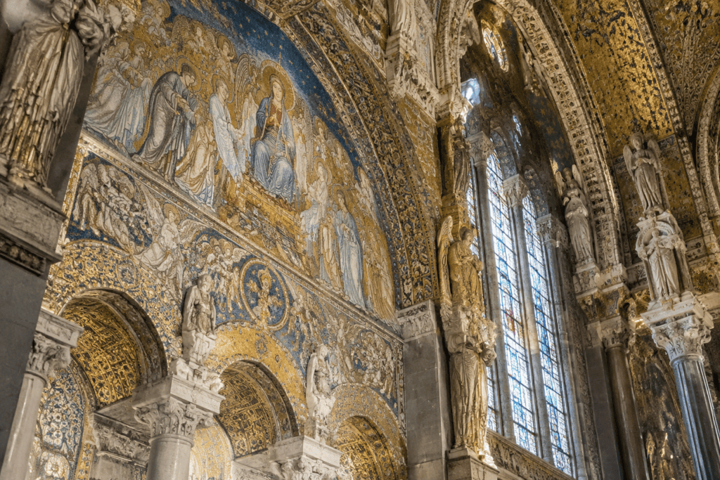Mosaïques dorées et bleues, figures sculptées et hautes fenêtres dans un intérieur de basilique.