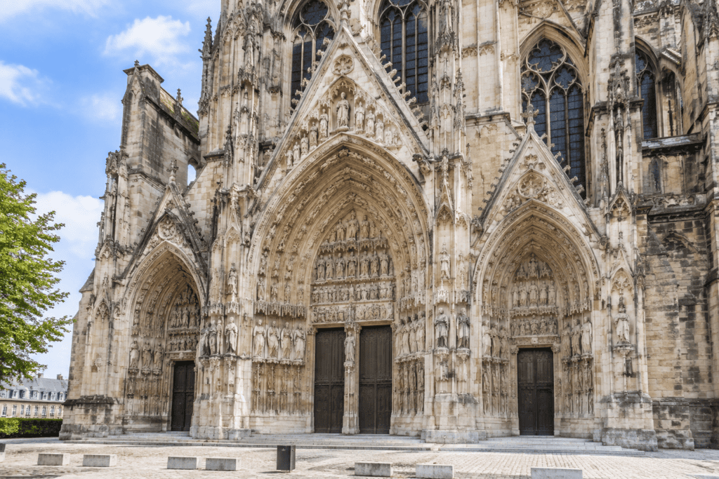 Trois portails gothiques sculptés sur la façade nord de la cathédrale Notre-Dame de Reims, avec un portail central plus large.