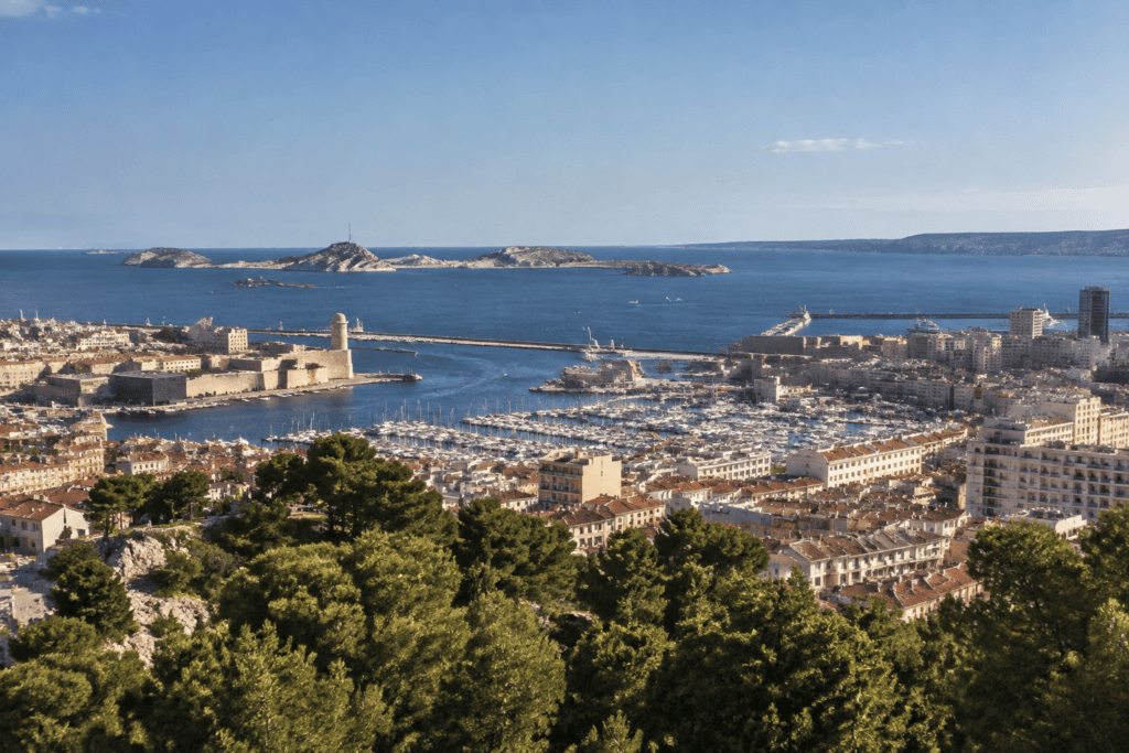 Panorama de Marseille avec le port, les forts du littoral, la mer et des îles à l’horizon.