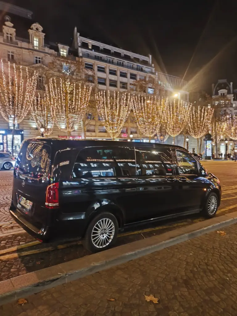 Vue latérale d’un van Mercedes noir devant les illuminations