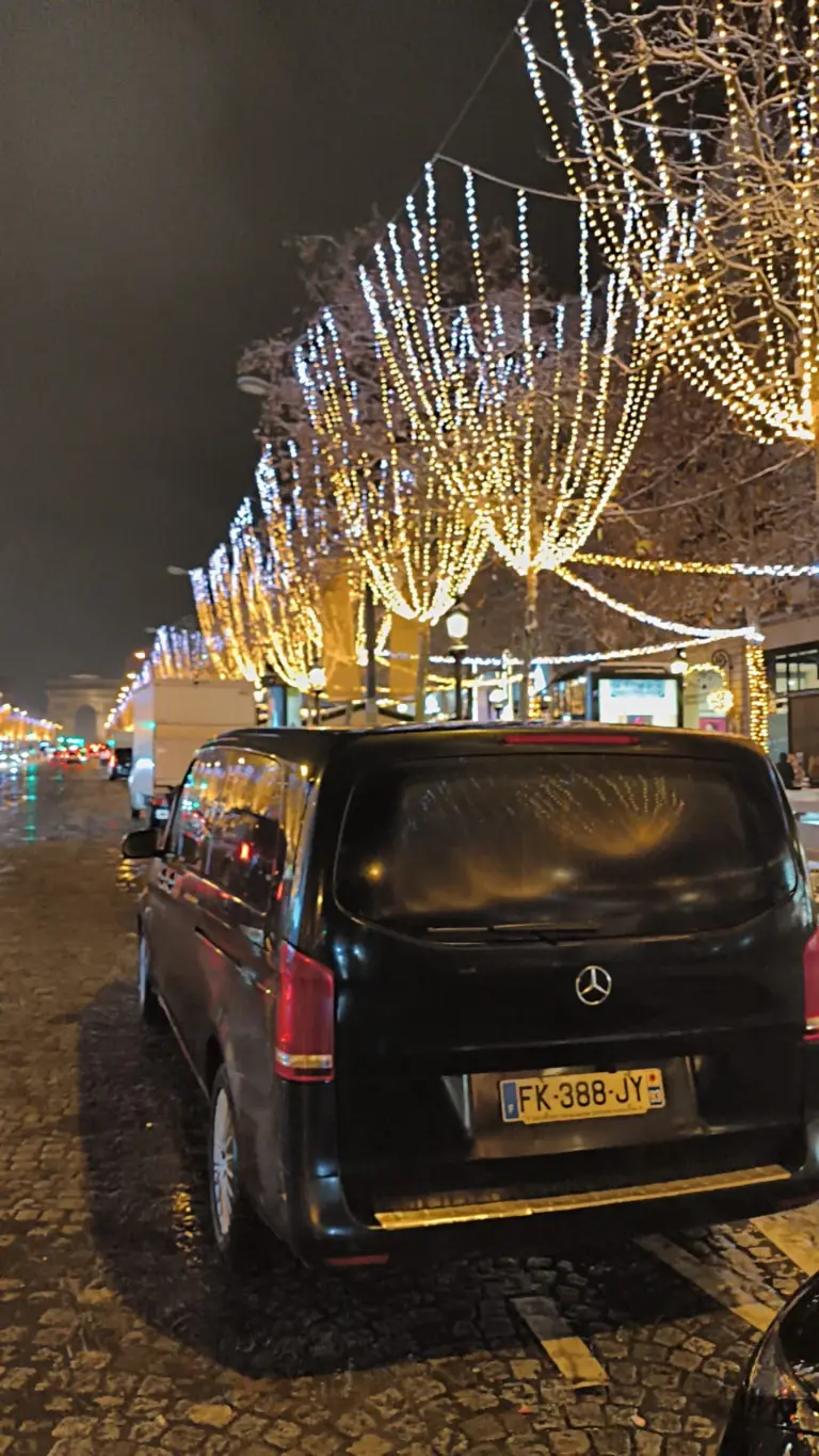 Vue arrière d’un van Mercedes noir sous les illuminations